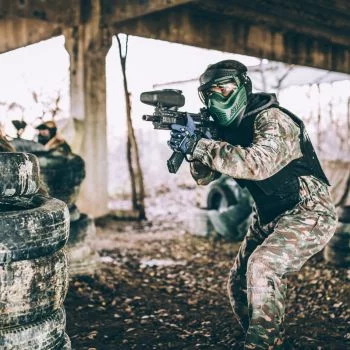 momak prikazan dok napreduje i osvaja teren na paintballu i nišani na protivnike