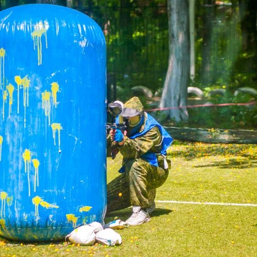 momak obučen u paintball odijelo nišani na protivnike iza velikom plavog čuna