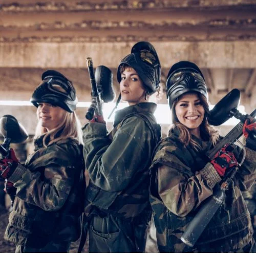 tri djevojke poziraju u paintball odijelima i paintball puškama
